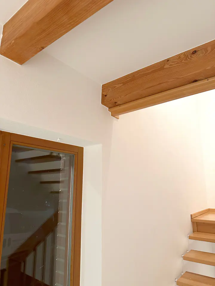 Glatt gespachtelte weiße Wände an einer Treppe mit Holzbalken