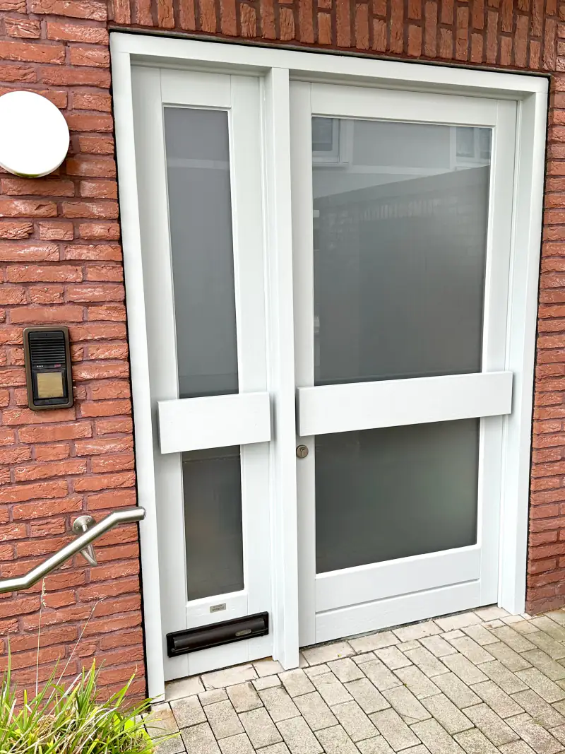 Weiß lackierte zweiflügelige Haustür in einer Klinkerfassade
